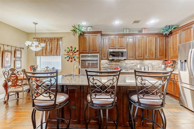 8215 Frontenac Dr, Houston, TX 77071 - kitchen with stainless steel appliances, a chandelier, light wood-style flooring, a center island with sink, and recessed lighting