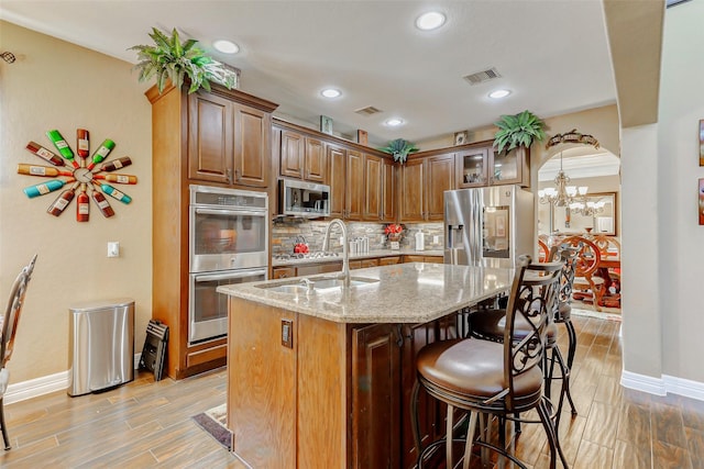 8215 Frontenac Dr, Houston, TX 77071 - kitchen with appliances with stainless steel finishes, a chandelier, baseboards, light stone counters, and a breakfast bar area