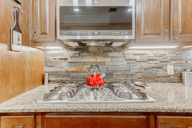 8215 Frontenac Dr, Houston, TX 77071 - kitchen with stainless steel appliances, tasteful backsplash, light stone counters, and brown cabinets