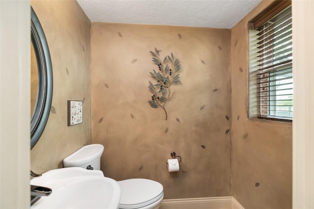 916 E James St, Baytown, TX 77520 - bathroom featuring toilet, a textured ceiling, baseboards, and a sink