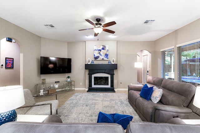 28515 Blue Holly Ln, Katy, TX 77494 - tiled living area with arched walkways, a ceiling fan, a fireplace with raised hearth, and baseboards