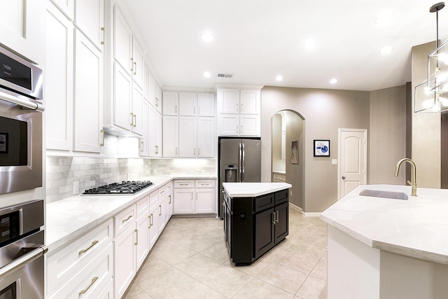 28515 Blue Holly Ln, Katy, TX 77494 - kitchen with a sink, a kitchen island, white cabinetry, arched walkways, and appliances with stainless steel finishes