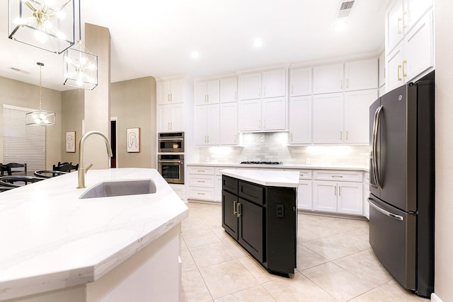 28515 Blue Holly Ln, Katy, TX 77494 - kitchen featuring appliances with stainless steel finishes, a kitchen island with sink, a sink, dark cabinetry, and white cabinetry