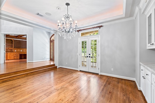 2042 Darby Ln, Fresno, TX 77545 - unfurnished dining area with french doors, light wood-style floors, a chandelier, a tray ceiling, and ornamental molding