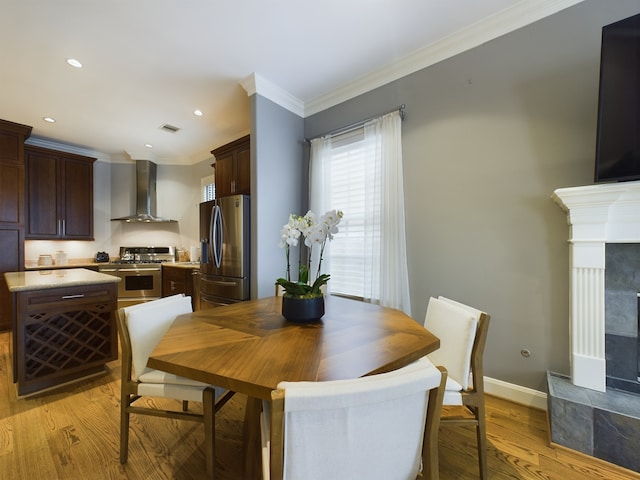 6319 Riverview Way, Houston, TX 77057 - dining area featuring a tiled fireplace, light wood-type flooring, ornamental molding, baseboards, and recessed lighting