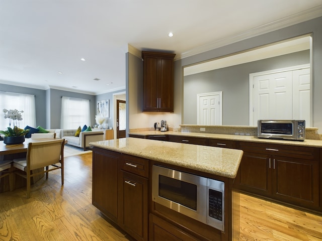 6319 Riverview Way, Houston, TX 77057 - kitchen with stainless steel microwave, crown molding, light wood finished floors, dark brown cabinetry, and light stone counters