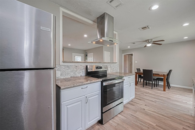 6134 Guadalupe St, Houston, TX 77016 - kitchen featuring appliances with stainless steel finishes, island range hood, backsplash, ceiling fan, and light wood finished floors
