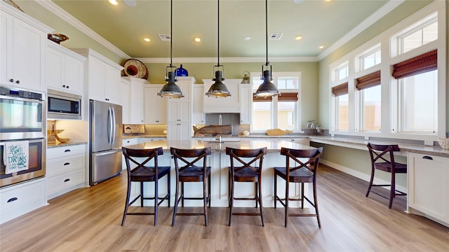 2414 Sand Drift Ln, Crystal Beach, TX 77650 - kitchen featuring appliances with stainless steel finishes, light wood finished floors, white cabinets, a kitchen breakfast bar, and ornamental molding