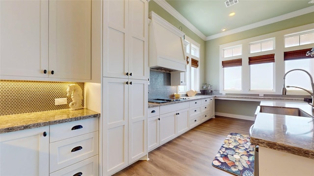 2414 Sand Drift Ln, Crystal Beach, TX 77650 - kitchen with a sink, ornamental molding, white cabinetry, cooktop, and backsplash