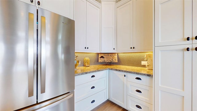 2414 Sand Drift Ln, Crystal Beach, TX 77650 - kitchen featuring freestanding refrigerator, white cabinetry, decorative backsplash, and light stone counters