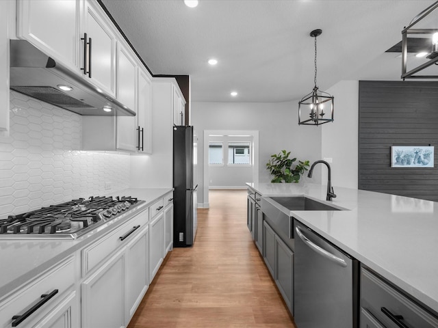 17511 Autumn Leaves Dr, Conroe, TX 77302 - kitchen featuring appliances with stainless steel finishes, a sink, under cabinet range hood, recessed lighting, and light wood-type flooring