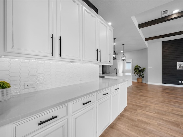 17511 Autumn Leaves Dr, Conroe, TX 77302 - kitchen with light countertops, white cabinets, tasteful backsplash, light wood-style floors, and a sink