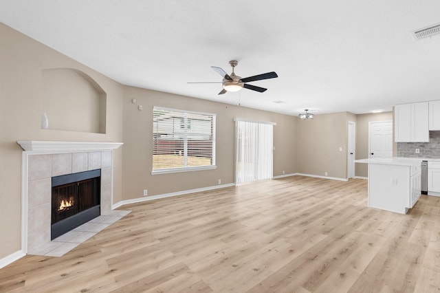 19222 Wading River Dr, Tomball, TX 77375 - unfurnished living room with light wood-type flooring, a tile fireplace, ceiling fan, and baseboards