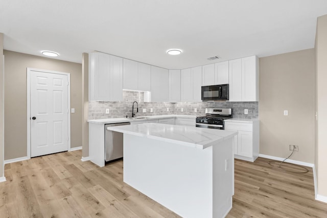 19222 Wading River Dr, Tomball, TX 77375 - kitchen featuring appliances with stainless steel finishes, tasteful backsplash, light wood-style floors, and a sink