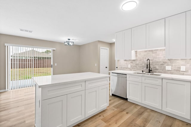 19222 Wading River Dr, Tomball, TX 77375 - kitchen featuring stainless steel dishwasher, a sink, tasteful backsplash, light wood-style floors, and white cabinets