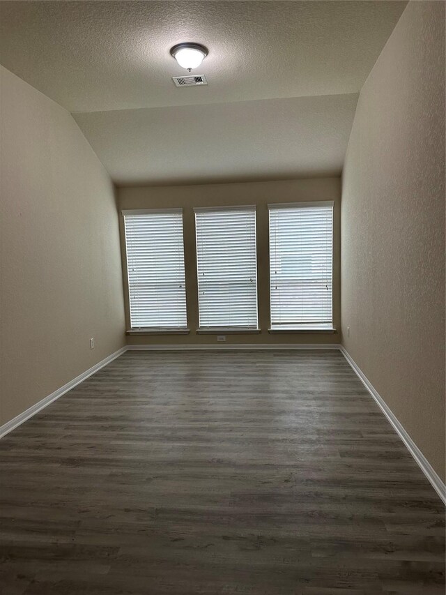 3423 Single Ridge Way, Katy, TX 77493 - unfurnished room with lofted ceiling, dark wood-style flooring, baseboards, a textured ceiling, and a textured wall