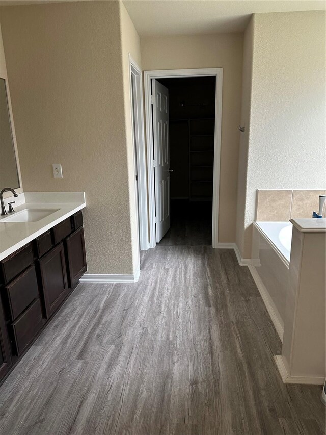 3423 Single Ridge Way, Katy, TX 77493 - full bathroom featuring wood finished floors, a textured wall, vanity, a bath, and baseboards