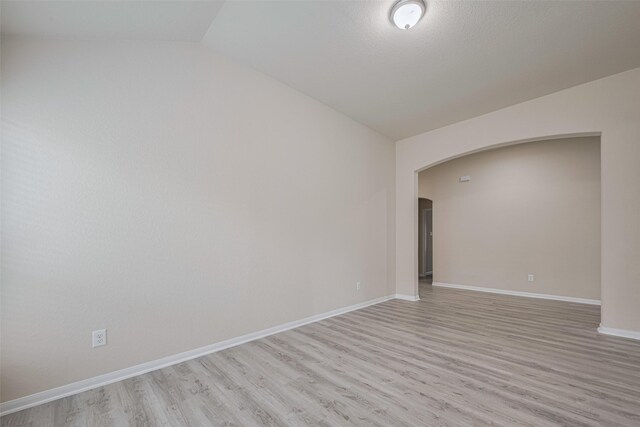 3423 Single Ridge Way, Katy, TX 77493 - empty room with arched walkways, light wood-type flooring, lofted ceiling, and baseboards