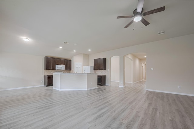 3423 Single Ridge Way, Katy, TX 77493 - unfurnished living room featuring vaulted ceiling, arched walkways, a ceiling fan, baseboards, and light wood-style flooring