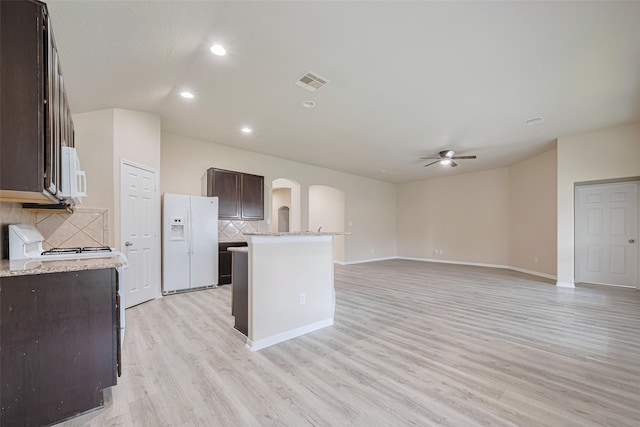 3423 Single Ridge Way, Katy, TX 77493 - kitchen featuring white appliances, dark brown cabinets, a ceiling fan, arched walkways, and decorative backsplash