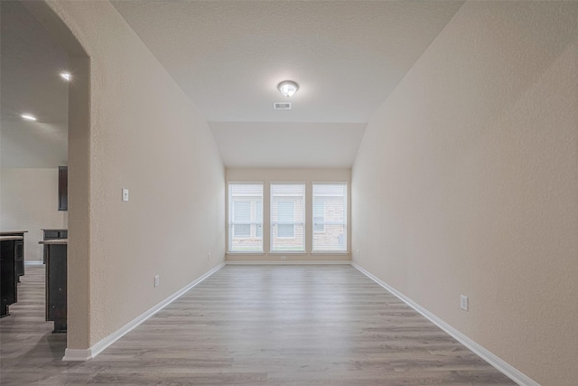 3423 Single Ridge Way, Katy, TX 77493 - unfurnished room with wood finished floors, vaulted ceiling, baseboards, arched walkways, and a textured wall