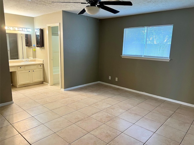 2503 Ironclad Dr, League City, TX 77573 - unfurnished bedroom featuring a textured ceiling, light tile patterned flooring, a sink, baseboards, and ensuite bath