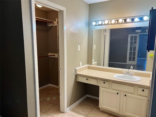 2503 Ironclad Dr, League City, TX 77573 - bathroom with tile patterned floors, vanity, a walk in closet, a textured wall, and baseboards