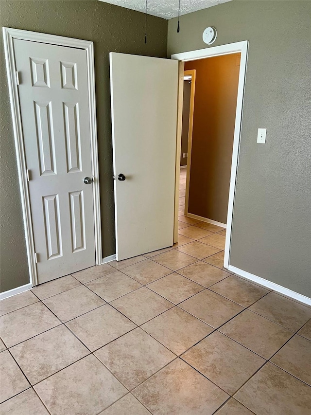 2503 Ironclad Dr, League City, TX 77573 - unfurnished bedroom with light tile patterned floors, a textured wall, and baseboards