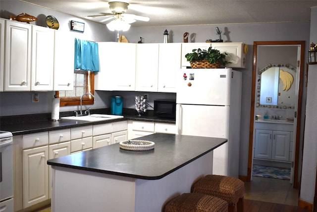 26656 Fm 457, Sargent, TX 77414 - kitchen with a sink, white appliances, dark countertops, ceiling fan, and white cabinetry