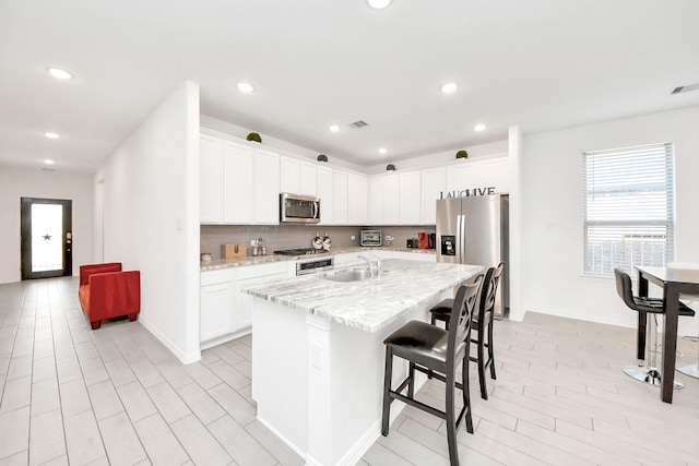 8034 Royal Palm Dr, Fulshear, TX 77441 - kitchen featuring stainless steel appliances, a sink, a kitchen bar, white cabinetry, and recessed lighting