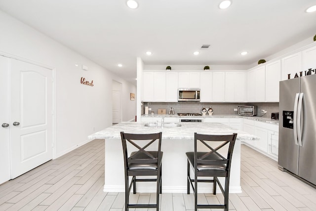 8034 Royal Palm Dr, Fulshear, TX 77441 - kitchen featuring stainless steel appliances, tasteful backsplash, a breakfast bar, a center island with sink, and recessed lighting