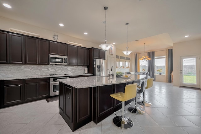 27003 Lindenwood Creek Ln, Katy, TX 77494 - kitchen with appliances with stainless steel finishes, light tile patterned flooring, a sink, a center island with sink, and backsplash