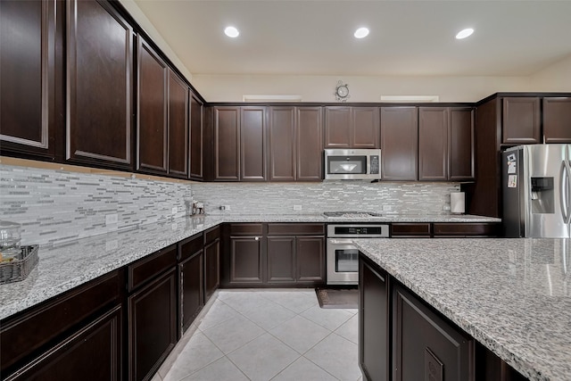 27003 Lindenwood Creek Ln, Katy, TX 77494 - kitchen featuring appliances with stainless steel finishes, light tile patterned floors, light stone counters, dark brown cabinets, and tasteful backsplash