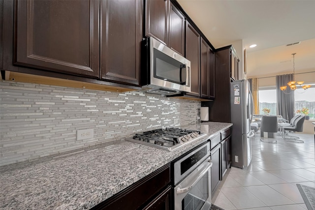 27003 Lindenwood Creek Ln, Katy, TX 77494 - kitchen featuring appliances with stainless steel finishes, a chandelier, dark brown cabinets, tasteful backsplash, and light tile patterned floors