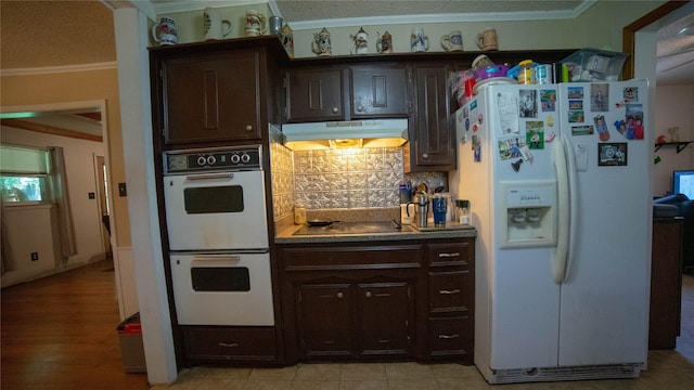 205 Mesa Dr, Gatesville, TX 76528 - kitchen featuring white appliances, under cabinet range hood, backsplash, dark brown cabinets, and crown molding