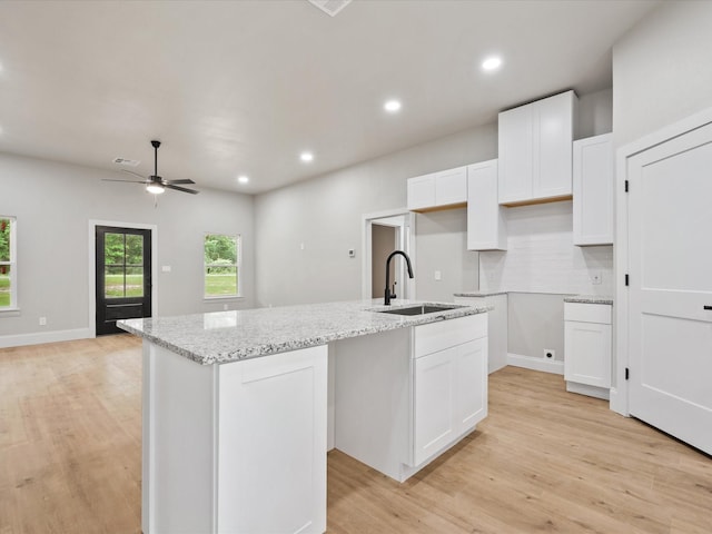 71 Prescott Dr, New Waverly, TX 77358 - kitchen featuring a sink, light wood-style flooring, a kitchen island with sink, white cabinetry, and recessed lighting