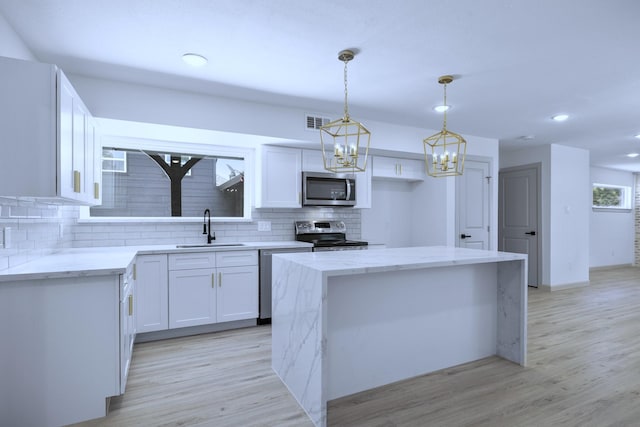 1405 Anne Ave, Humble, TX 77338 - kitchen with stainless steel appliances, a sink, backsplash, a center island, and light wood-type flooring