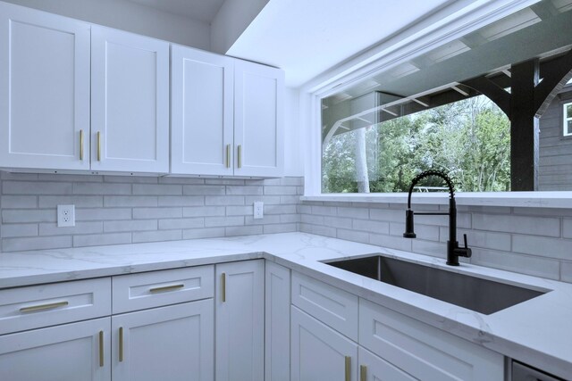 1405 Anne Ave, Humble, TX 77338 - kitchen featuring a sink, decorative backsplash, white cabinets, and light stone counters