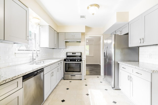 5247 Ariel St, Houston, TX 77096 - kitchen featuring stainless steel appliances, a sink, under cabinet range hood, light stone counters, and backsplash