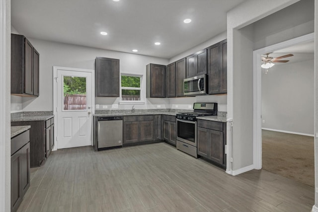 24742 Russet Bluff Trl, Houston, TX 77336 - kitchen with stainless steel appliances, a ceiling fan, light wood finished floors, a sink, and light stone counters