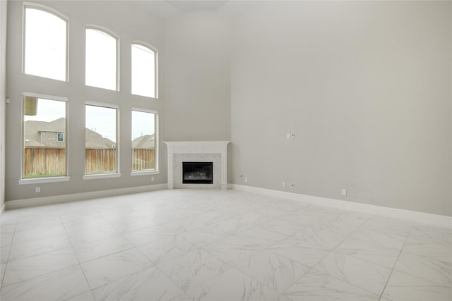 26510 Crimson Bluff Ln, Katy, TX 77494 - unfurnished living room with baseboards, light marble finish floors, a premium fireplace, and a towering ceiling