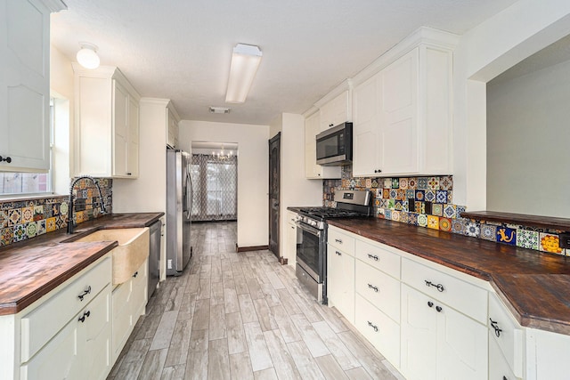 18530 S Wimbledon Dr, Katy, TX 77449 - kitchen with wooden counters, stainless steel appliances, a sink, decorative backsplash, and white cabinets