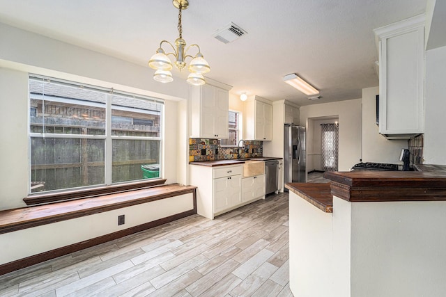 18530 S Wimbledon Dr, Katy, TX 77449 - kitchen with appliances with stainless steel finishes, a chandelier, white cabinetry, light wood finished floors, and decorative backsplash