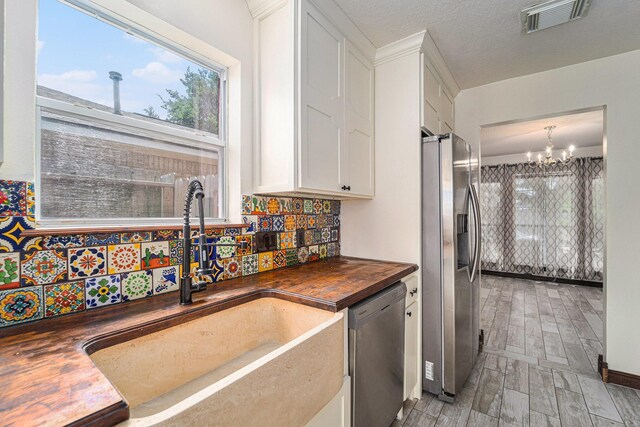 18530 S Wimbledon Dr, Katy, TX 77449 - kitchen featuring appliances with stainless steel finishes, wood counters, a sink, a chandelier, and white cabinetry