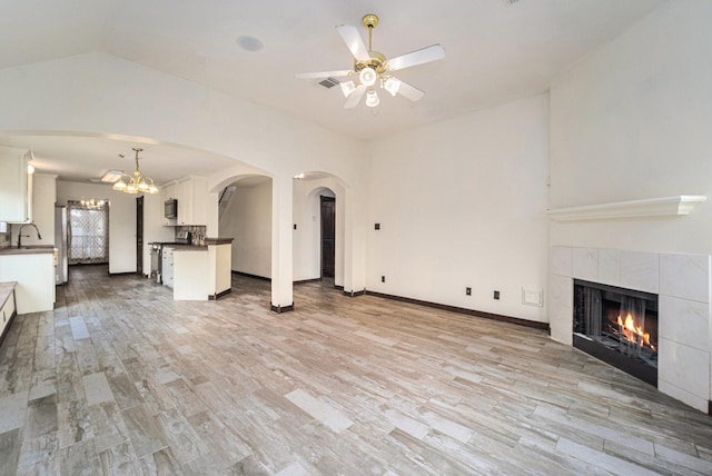 18530 S Wimbledon Dr, Katy, TX 77449 - unfurnished living room featuring ceiling fan, a tile fireplace, light wood-type flooring, a sink, and vaulted ceiling