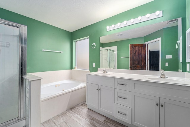 18530 S Wimbledon Dr, Katy, TX 77449 - bathroom with double vanity, a shower stall, a bath, wood finished floors, and a textured ceiling