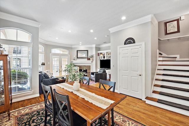 18731 Egret Oaks Ln, Webster, TX 77058 - dining room with crown molding, wood finished floors, a fireplace, stairway, and french doors