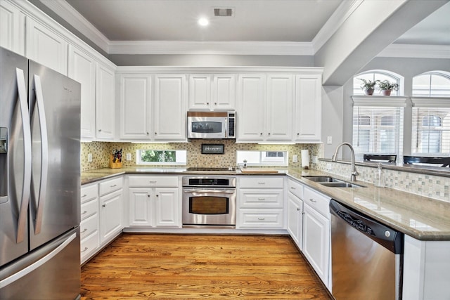 18731 Egret Oaks Ln, Webster, TX 77058 - kitchen featuring stainless steel appliances, a sink, ornamental molding, white cabinetry, and recessed lighting