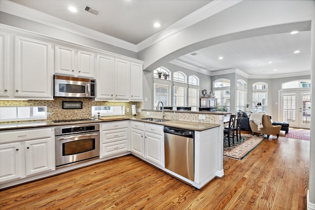 18731 Egret Oaks Ln, Webster, TX 77058 - kitchen featuring stainless steel appliances, a sink, light wood-style flooring, a peninsula, and recessed lighting