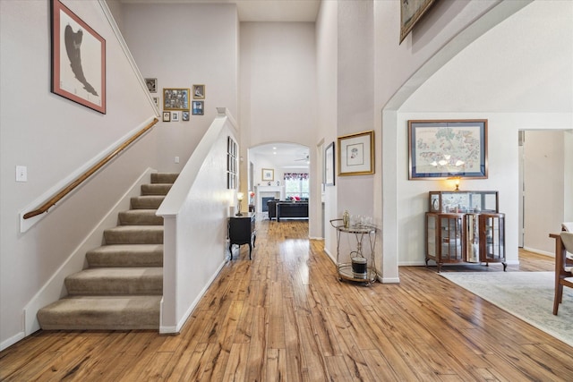 18719 Cypress Lake Village Dr, Cypress, TX 77429 - entryway featuring light wood-type flooring, arched walkways, stairs, a towering ceiling, and baseboards